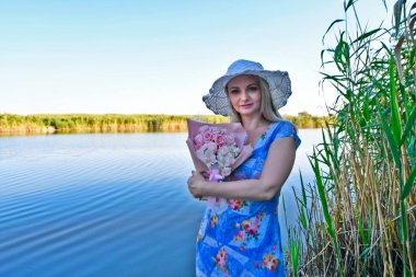 Yazın akşamları güzel bir kadın bir buket ayçiçeği ve bir buket gülle gölde..