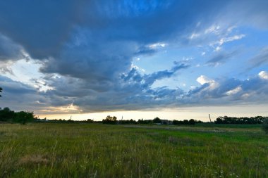Yaz yağmurundan sonra güzel bir yaz manzarası, gün batımında şehir dışında, köyde. Ukrayna, Dnipropetrovsk bölgesi.