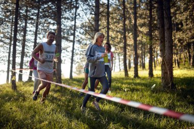Bir grup sporcu ormanda koşuyor.