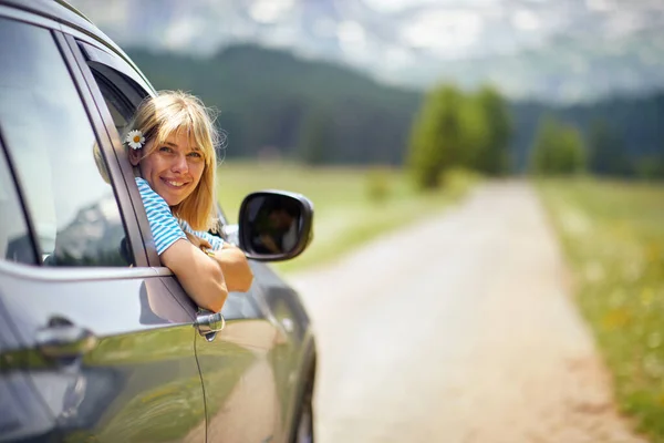 美しいブロンドの女性は髪の毛で花と笑っている 車の後部ビュー 道路交通 自然概念 — ストック写真