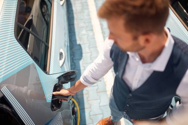 Benzin istasyonunda yakıt ikmali yapılan erkek arabasının en üst görüntüsü.