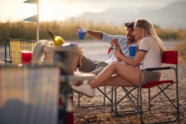 Karavanın önünde kutlama yapan mutlu genç çift. Seyahat ve dostluk kutlamaları. 