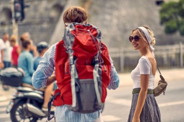 Güzel sarışın kadın sırt çantalı adama bakıyor. Şehirde yaz yürüyüşü. Turistler, çiftler, seyahat, eğlence konsepti.