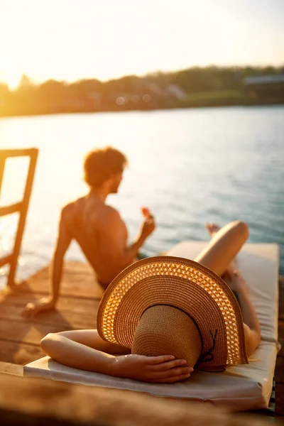 青い水の日光浴でカップル 休暇で若い男と女 ライフスタイルの概念 — ストック写真