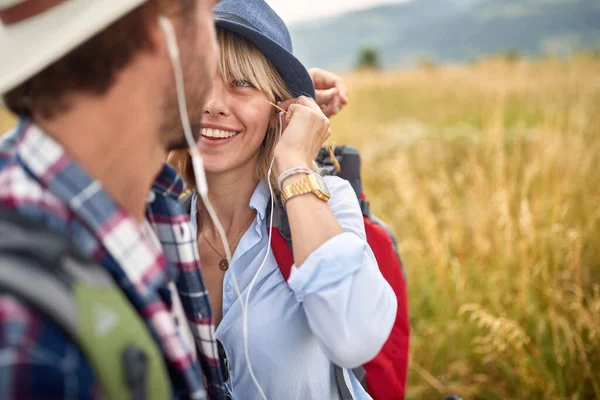 幸せな晴れた日 自然の中で旅をし 一緒にヘッドフォンのリスニング音楽を共有するカップルを笑顔 — ストック写真