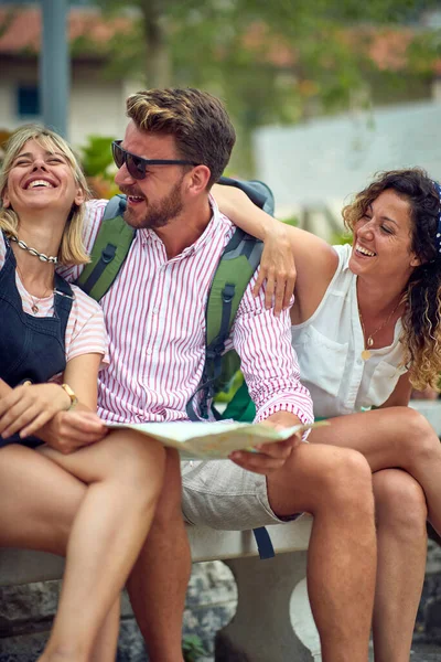 Młodzi Przyjaciele Ławce Trzymający Mapę Śmiejący Się Turyści Bawiący Się — Zdjęcie stockowe