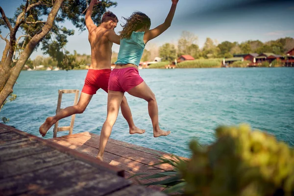Pareja Saltando Agua Embarcadero Madera Joven Mujer Divirtiéndose Juntas Vacaciones —  Fotos de Stock