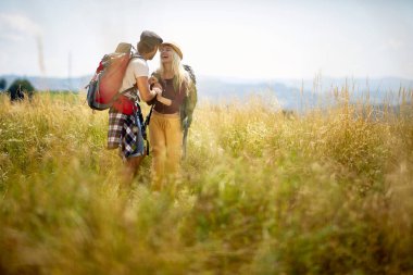 Genç mutlu çift, doğada güneşli bir günde yürürken sohbet ediyorlar. Yürüyüş, ilişki, doğa, aktivite