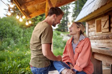 Mutlu çift birbirine bakıyor ve ahşap kulübede dinleniyor.