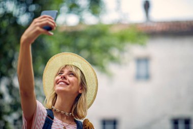 Güzel bir günde deniz kenarında bir tatil sırasında eski şehirde yürürken selfie çeken genç bir kızın yakın çekimi. Tatil, deniz kenarı, turist