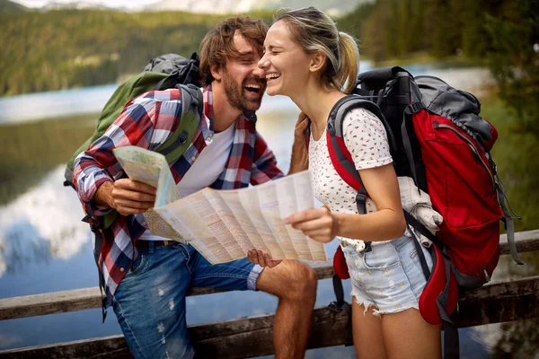湖のそばに笑顔の男と女の子 バックパックを持つカップル観光客屋外 — ストック写真