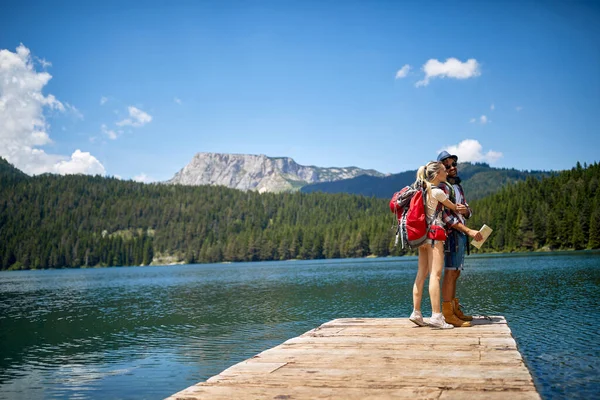 幸せな若いカップルは湖でリラックスします ハイキングのコンセプト — ストック写真