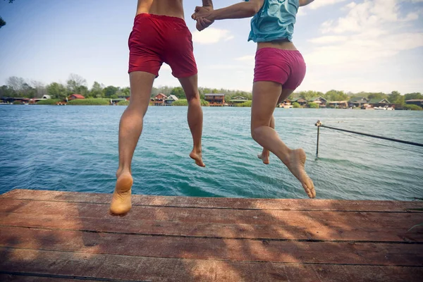 Glückliche Männer Und Frauen Springen Von Einem Steg Ins Wasser — Stockfoto