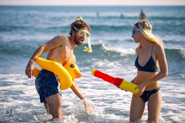 幸せ若いです男と女の子とともに水のおもちゃは海でビーチで楽しいです — ストック写真