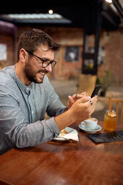 Snygg Ung Man Caféet Sitter Ensam Vid Bordet Och Rullar — Stockfoto