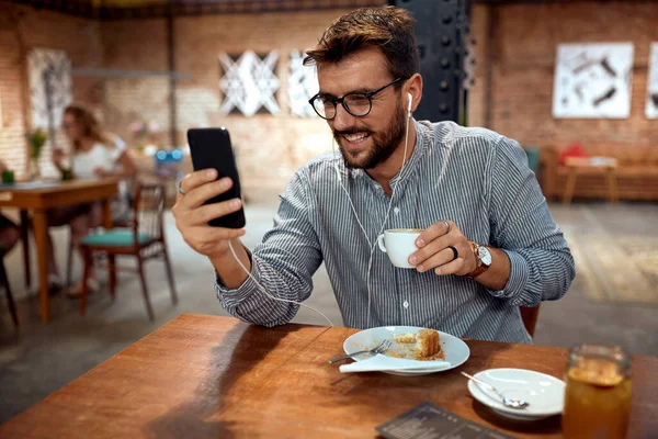 Ung Stilig Man Sitter Café Njuter Kaffe Och Tittar Smartphone — Stockfoto