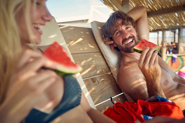 若い魅力的なカップルのビーチでの休暇を楽しんで 日焼け止めスイカを食べるに横たわっている レジャー ライフスタイルのコンセプト — ストック写真