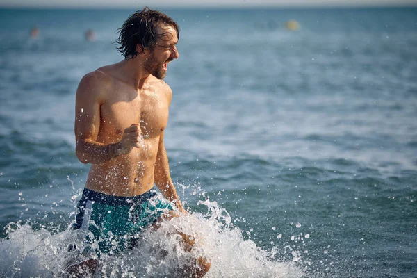 幸せな男はビーチで水遊び — ストック写真