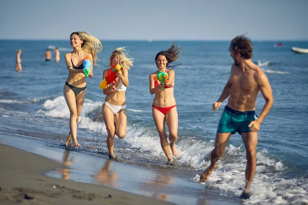 Jovens Amigos Felizes Com Armas Água Divertir Praia Mar — Fotografia de Stock