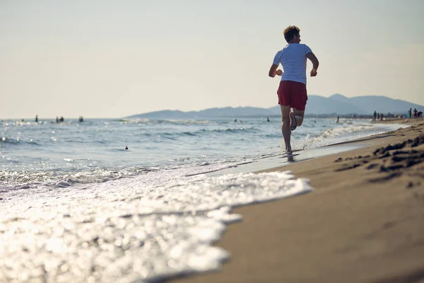 ランナー 海岸を走っている若者たち 健康的なライフスタイルを実践する太陽を楽しむビーチでジョギングするアスレチック魅力的な人々 — ストック写真