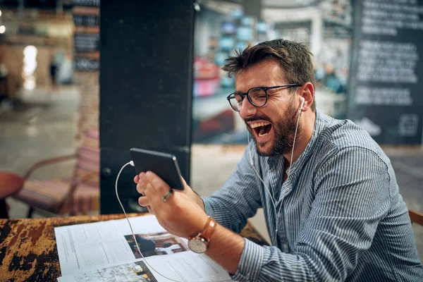 Όμορφος Χαρούμενος Νεαρός Άνδρας Γυαλιά Και Ακουστικά Που Χρησιμοποιεί Smartphone — Φωτογραφία Αρχείου