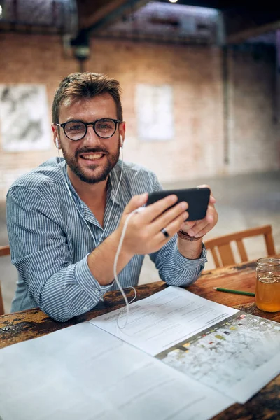 Attraktiv Ung Man Caféet Sitter Ensam Håller Smartphone Och Ler — Stockfoto