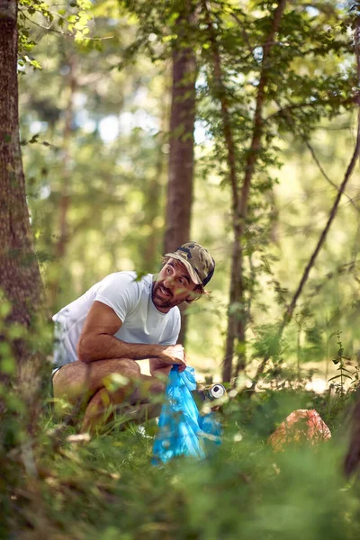 若い男が屋外でゴミを拾い 自然清掃ボランティア生態緑のコンセプト — ストック写真