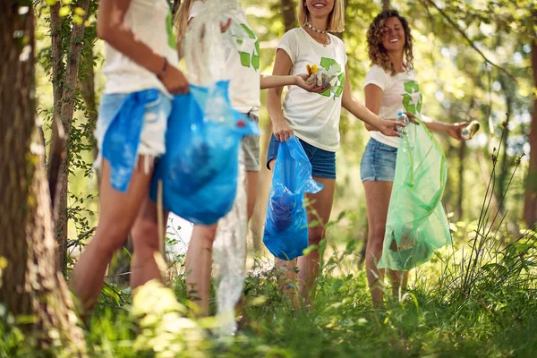 美しい夏の日に森の中でゴミを収集しながら楽しい時間を過ごしている若いハンサムな女性生態活動家のグループ 生態系 — ストック写真