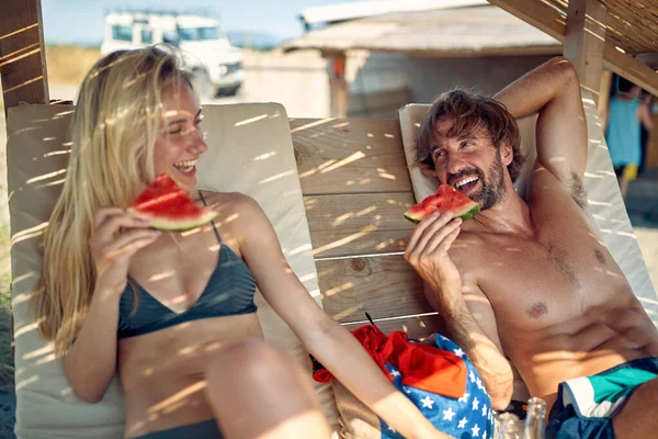 幸せな男と女はビーチで休暇中に一緒にスイカをリラックスして食べる — ストック写真