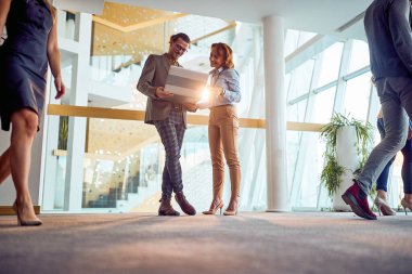 İki iş arkadaşı koridorda hoş bir atmosferde durup dizüstü bilgisayarın içeriğini izliyorlar. İş, insanlar, şirket.