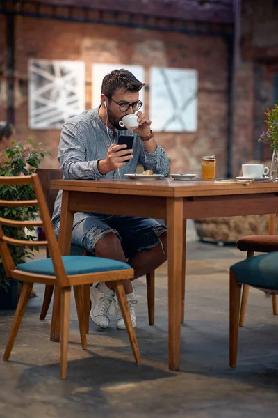 Mladý Hipsterský Muž Sluchátky Sedí Jídelně Pije Kávu Baví Kávy — Stock fotografie