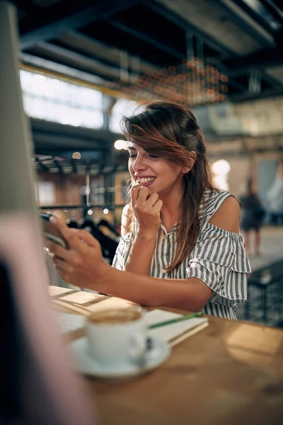 可爱的年轻女商人在一个富有创意的办公室里看着智能手机 享受着咖啡休息时间 首席执行官概念 — 图库照片