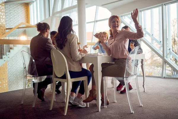 若いビジネスマンは 会社の建物内のフレンドリーな雰囲気の中で昼食休憩中にテーブルの周りに座っており ピザを食べながら楽しい時間を過ごしています ビジネス — ストック写真