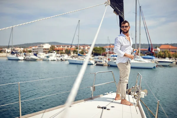 ヨットの船首に立って 美しい晴れた日に海辺の町の景色を楽しむ若い男 — ストック写真