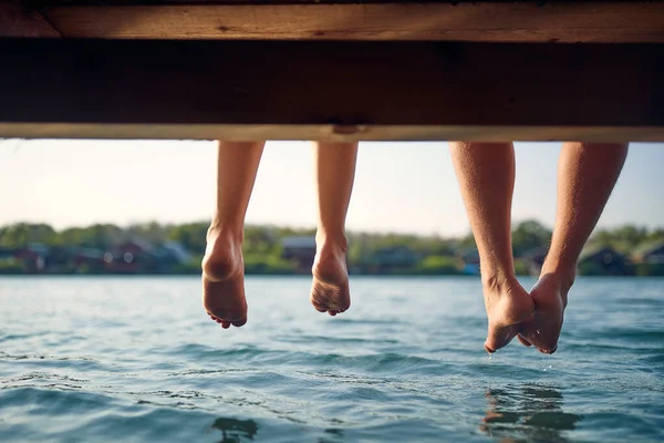 夫婦は足を垂らして水で木製の桟橋に座っている 足の後ろのビュー 楽しい 質の高い時間 レジャー ライフスタイルの概念 — ストック写真