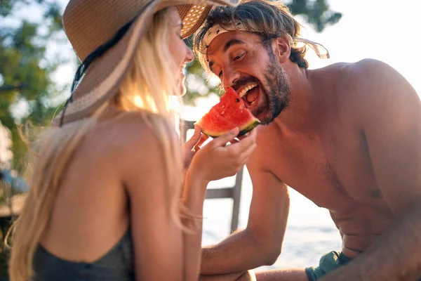 ロマンチックな幸せな男と女をリラックスし 一緒に夕日にスイカを食べる — ストック写真