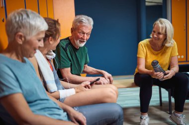 Bir grup son sınıf öğrencisi antrenmandan sonra soyunma odasında konuşuyorlar ve neşeliler. Kadın ve erkek birlikte. Sağlık, yaşam tarzı, yaşlılık konsepti.