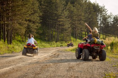 Neşeli bir grup arkadaş, doğada güneşli bir günde dörtlü sürerken heyecanlıdır. Binicilik, arkadaşlık, doğa, aktivite