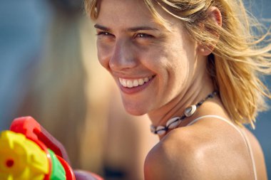 Sahilde elinde su tabancasıyla güzel bir kadının portresini yakın plan çek. Tatil, eğlence, yaşam tarzı konsepti.