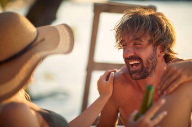 Yaz günbatımında genç bir kızla birlikte rıhtımda gülümseyen bir adam.