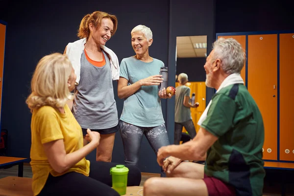 水平拍摄更衣室里的人 老人和两个女人与年轻的教练在锻炼前进行了愉快的交谈 生活方式概念 — 图库照片