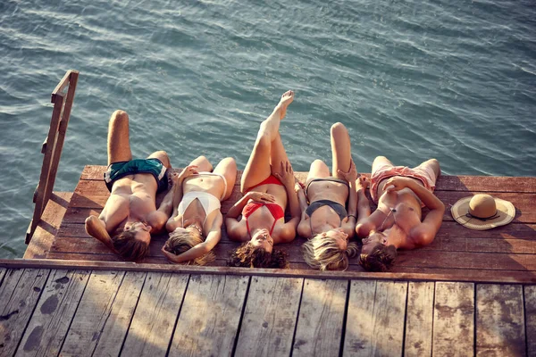 Grupo Jóvenes Amigos Acostados Embarcadero Madera Junto Agua Tomando Sol —  Fotos de Stock