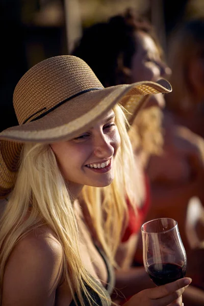 若い笑顔の女の子は日没時に水でドックでワインを飲みます — ストック写真
