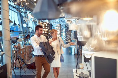 Mutlu bir çift mobilya mağazasında çeşitli lamba ve lambaları karıştırıyor..