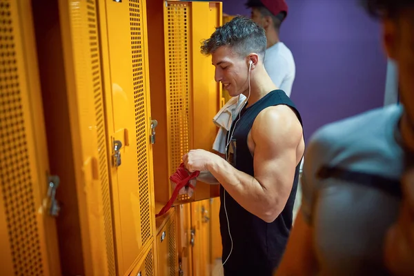 年轻男子在健身房更衣室里锻炼后 从手中接过红色的防护带 生活方式概念 — 图库照片