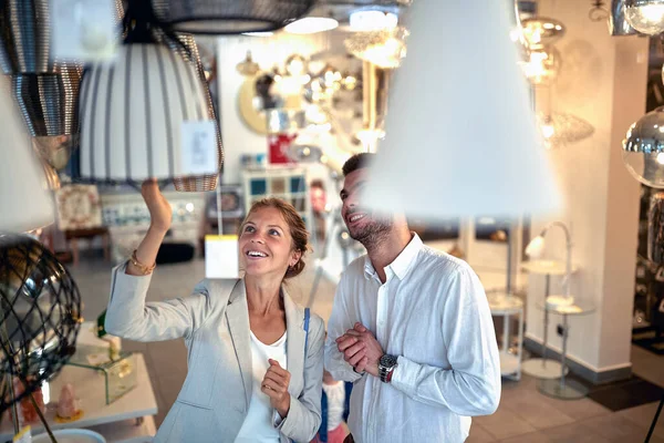 一对年轻夫妇在一家灯具店里 兴奋而快乐地浏览着吊灯和灯笼 — 图库照片