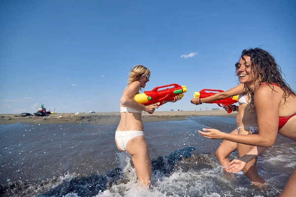 Tři Dívky Plavkách Baví Velkými Vodními Pistolemi Břehu Togetherness Fun — Stock fotografie
