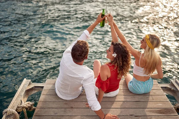 Bir Grup Arkadaş Kıyısındaki Ahşap Iskelede Bira Içip Kadeh Kaldırıyorlar — Stok fotoğraf
