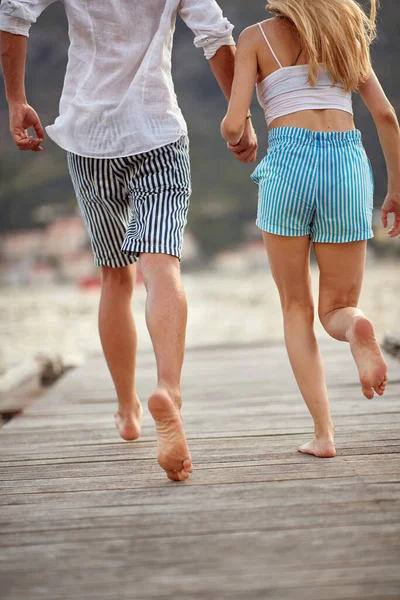在一个美丽的日子里 一对年轻夫妇手牵手在海滨的码头上奔跑 — 图库照片