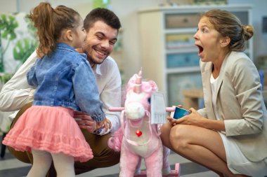 Güzel bir aile, küçük kızlarına mobilya dükkanından sallanan bir at alıyor. Neşeli ve heyecanlı hissediyorlar. Yaşam tarzı kavramı.